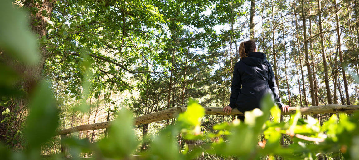 Frau sitzt auf einem umgefallenen Ast im Wald